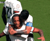 a soccer player with the number 8 on his armband is hugging another player