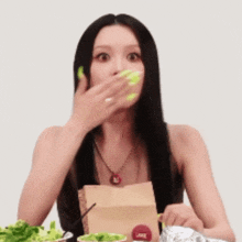 a woman covering her mouth with her hand while holding a bag that has the word juice on it