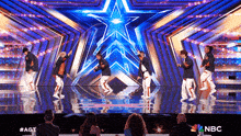 a group of young men are dancing on a stage in front of a star .