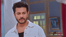 a man with a beard is wearing a white shirt and black shirt .