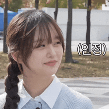 a girl with braided hair is smiling in front of a sign that says " ( ) "