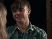 a young man wearing a plaid shirt is looking at a woman