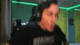 a man wearing headphones and a black t-shirt is making a funny face .