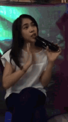 a woman singing into a microphone with a purple background