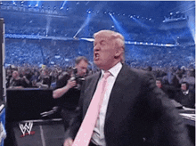 a man in a suit and tie is standing in front of a crowd at a wrestling event