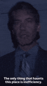 a man in a suit and tie with the words " the only thing that haunts this place is inefficiency " below him