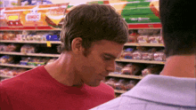 a man in a red shirt stands in front of a bimbo display