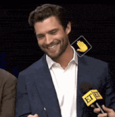 a man in a suit is being interviewed by someone holding a microphone that says et