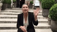 a woman is sitting on a set of stairs waving
