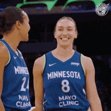 two female minnesota basketball players are smiling and looking at each other