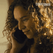 a woman with curly hair is talking on a cell phone with the word contour on the bottom right