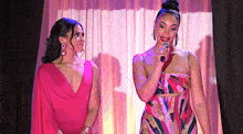 two women in pink dresses are standing next to each other on a stage .