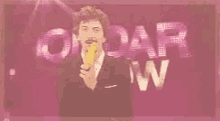 a man in a suit is holding a corn on the cob in front of a sign that says omar swan .