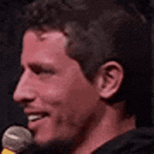 a close up of a man 's face with a microphone behind him