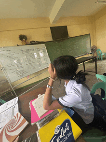 a girl sits at a desk in front of a white board that says mathematical facts