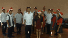 a group of people wearing santa hats are standing in a room