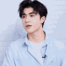 a young man wearing a light blue shirt is making a face