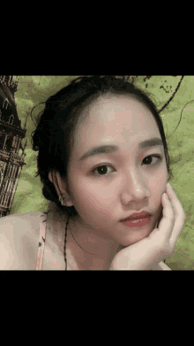a woman with her hand on her face is laying on a bed