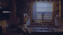a woman is sitting in a kitchen near a sink