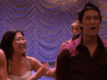 a man in a red shirt is pointing at a woman in a white tank top