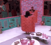a woman in a brick costume is standing in front of a brick wall in a room .