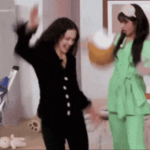 two women in pajamas are dancing in a room with a stuffed animal .