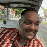 a man in a red and white shirt is smiling while sitting in a cart