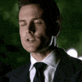 a man in a suit and tie is looking down with his eyes closed