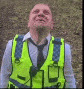 a man wearing a yellow vest and tie looks up at the sky .