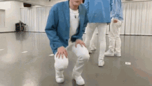 a man in a blue jacket is kneeling down in a dance studio .