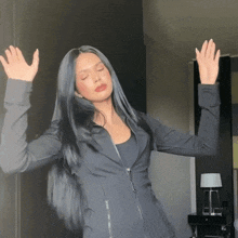 a woman in a black jacket is dancing with her arms in the air