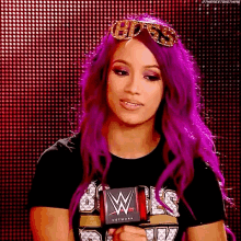 a woman with purple hair is holding a microphone in front of a red background .