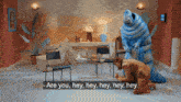 a woman kneeling down in front of a blue monster that says " are you hey hey hey hey hey "