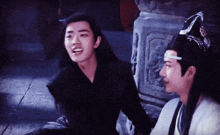 two young men are sitting next to each other on the floor and talking .