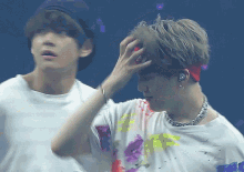 a man wearing a headband holds his hand to his head while another man looks on