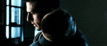 a man holds another man 's head in his arms in a dark room