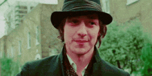 a man wearing a hat and a black jacket is smiling .