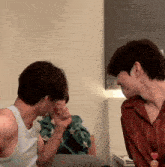 two men are touching each other 's faces in a room with a smiley face in the corner