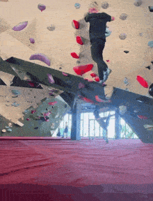 a man climbs a climbing wall with a purple carpet