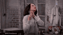 a woman in a grey sweater is holding a spray bottle in her hand ..