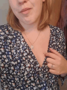 a woman wearing a floral dress and a necklace with the letter a on it