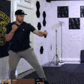 a man in a black shirt and gray pants is standing in a room with a sign that says " keep fit "
