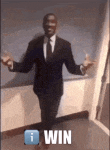 a man in a suit and tie is standing in a hallway and says win