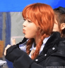 a girl with red hair is wearing a black jacket and braids