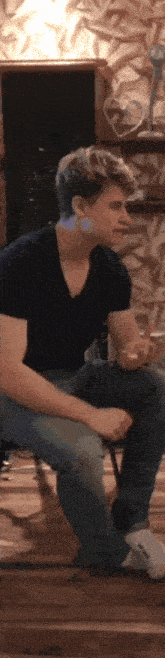 a man in a black shirt is sitting on a chair with another man .