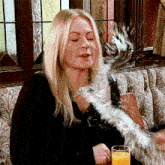 a woman is sitting at a table with a glass of orange juice in her hand