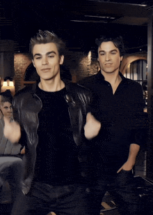 two men are dancing in a dark room with a woman sitting in the background