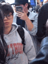 a man taking a picture of himself in a crowd while wearing a sweatshirt that says " gates "