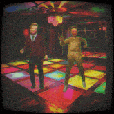 two people are dancing on a colorful dance floor in a dark room