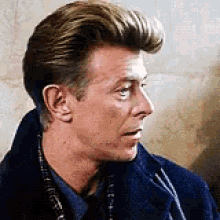 a close up of a man 's face wearing a blue coat and a plaid shirt .